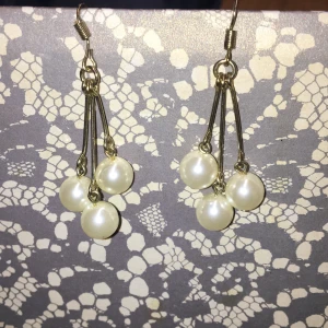 Guldfärgade örhängen  - Hängande örhängen med stora fina pärlor. Näst intill aldrig använda. Säljes för att jag inte använder denna typ av örhängen.