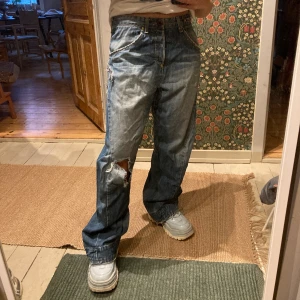 Levi’s baggy jeans - Baggy jeans från Levi’s med slitet hål på ena knät. Står ingen storlek i byxorna men passar allt från XS-L då midjan är justerbar där bak (se bild 3). Sitter då väldigt snyggt med lite tajtare i midjan och lösare över benen!  Köparen står för frakt! OBS jag är 160 cm och bär S. 