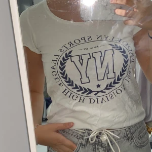 Vit t-shirt  - En vit t-shirt i skönt material från Gina Tricot i storlek XS, har ett blått tryck på bröstet och är använd ett fåtal gånger.