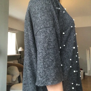 Zara grå stickad t-shirt med pärlor - Tunnstickad t-shirt med vita pärlor på framsidan. Rätt lång på mig som är 163 cm. Knappt använd. Köpt för 350 kr, säljer för 100 kr. Skönt mjukt material.