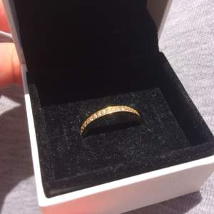 Jag säljer min ring som är från guldfynd. Sparsamt använd. Materialet är i guldfärgat silver med vita stenar längs hela översidan.  Storlek 17 motsvarar ca 55