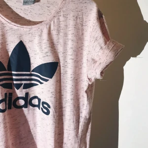  - Rosa Adidas t-shirt med mörkblått tryck. Liten i storleken och har passat på mig som har medium! Använd någon gång. 