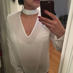  - Fintröja med liten v-ringad öppning vid bröstet. Liknande ”siden” material. Stängning baktill (halsen) med knäppning. 