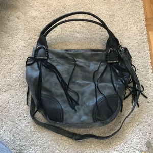  - Väska med 1 ytterfack och 4 innerfack + delning i mitten, använd kanske 2 eller 3 gånger. En liten skada på ena remmens fäste, syns på bild 3  Obs! Finns spår av katthår i fodret