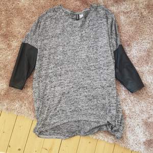 svart/vit stickad tröja i längre modell med 3/4 arm.   snygg läder detalj på ärmarna 