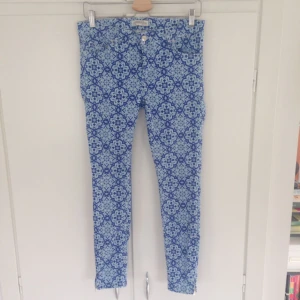  - Jättefint mönstrade blåa byxor från Zara. Knapp och gylf fram, fickor både fram och bak.   En liten silver-kedja vid ankeln. "croppade", så en modell som ska sluta vid ankeln dvs lite kortare. Jättefint skick!