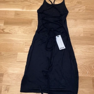 Klänning med korsad rygg - Klänning i storlek XS/S som man knyter bak i ryggen, ser liten ut på bild men stretchigt material. Aldrig använd