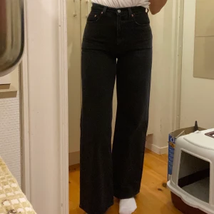 Levis Ribcage wide leg jeans - Svarta Levi’s Ribcage jeans. Byxmodellen är lång i benen. Bra skick. Köpte de i Januari. Säljer för att det är fel storlek för mig just nu. Nypris 1149kr. Säljes för 350 kr. Köparen står för eventuell frakt. Kan mötas upp i Uppsala :)