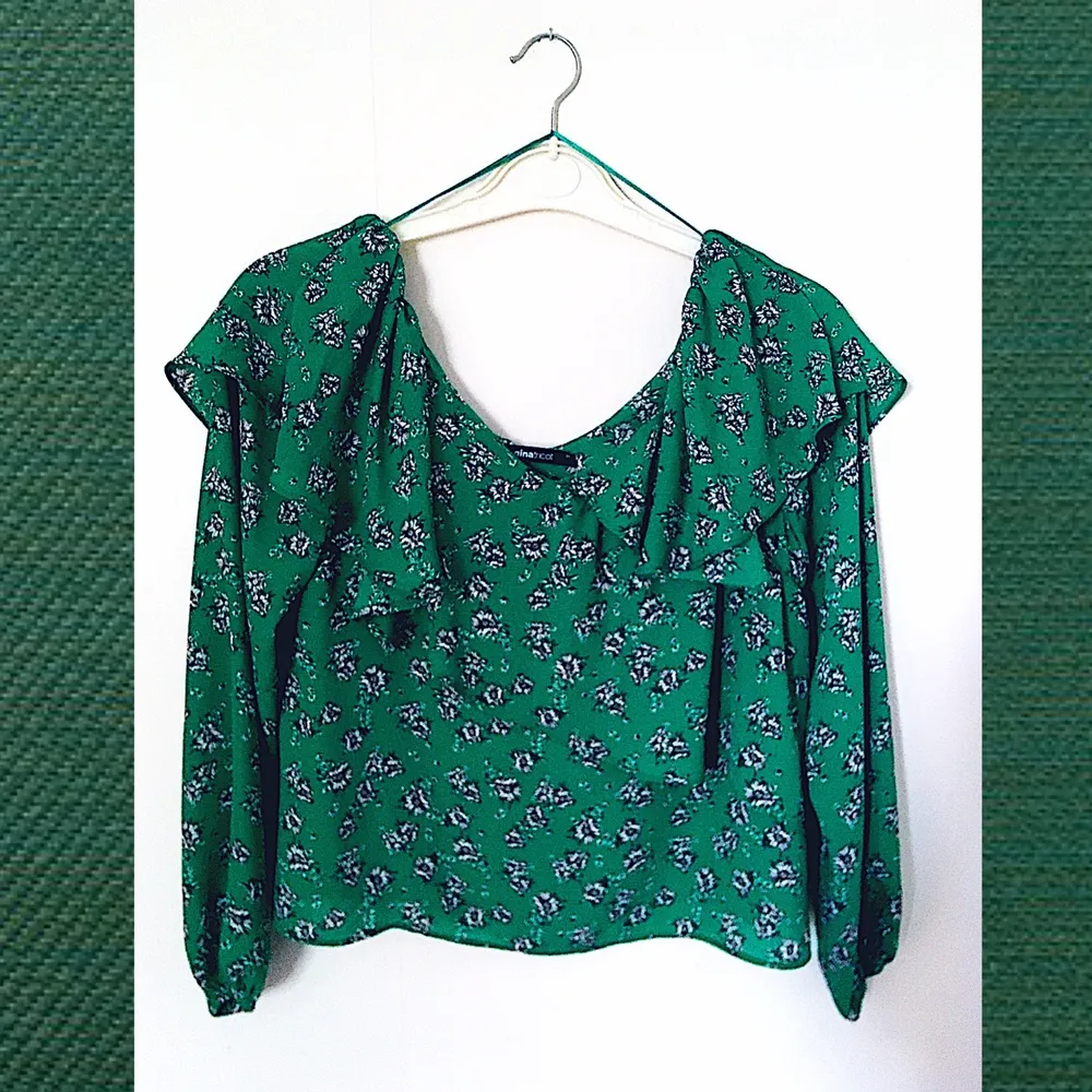 Grönblommig blus(artad) tröja från Gina Tricot i storlek 34, går ner över axlarna och ligger över barmen i volanger. Skirt och luftigt tyg (dock inte genomskinlig). Helt oanvänd med prislappen kvar!. Tröjor & Koftor.