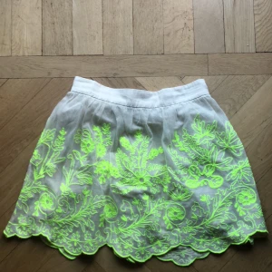 Sommarkjol - Sommarkjol i två lager där det övre lagret har broderi i neonfärg. Sparsamt använd, som ny! Upphämtning prioriteras