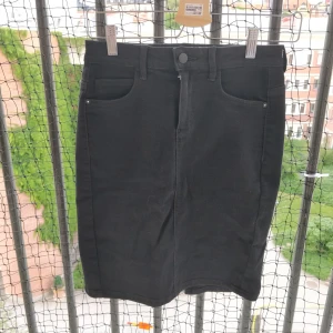 Knälång jeanskjol i stretch  - Svart strechigkjol med slits bak. Sjukt snygg passform! Möts helst upp annars tillkommer frakt! 