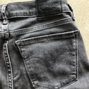 Levis jeans - Säljer ett par svarta/gråa Levis jeans i st 25 modell 710 ”super skinny”. Dom har en liten lagad slitning på knät som man kan se på bild 3. Men är bara använda ett fåtal gånger pågrund utav att dem tyvär är lite försmå för mig. Köpt på NK för 1000 kr