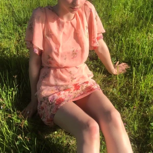 Sommarklänning - Jättefin sommarklänning i rosa-peach färg. Kort, går över knäna på mig som är 165 cm. Mönster av fjärilar, blommor och blad. Riktigt somrig. ☀️ Frakt 20kr, avhämtning funkar också 🌸