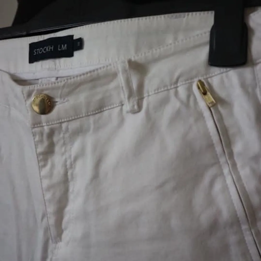 Säljer ett par vita chinos med guld detaljer både vid fickorna och nere vid byxbenet. Byxorna är köpta från Mq och är i nytt skick! Storlek: 38. Jeans & Byxor.