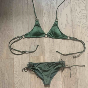 Grön bikini - Grön bikini med knytdetaljer. Gulddetaljer i överdelen. Köpt från h&m i storlek 34. Aldrig använd, frakt ingår.