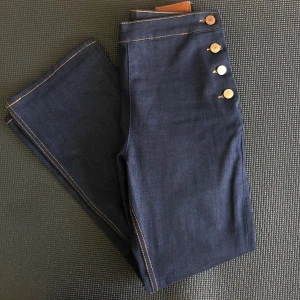Sailorjeans med knappar - Så söta jeans! Köpta här men aldrig använda. Ankellånga med utställda ben. Betalning sker med Swish. Köparen stån för frakten. Kan också hämtas upp i Hökarängen, Sthlm. 💙