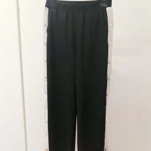 Popper pants - Byxor med knappar och vita ränder på sidorna, från Missyempire i storlek S. Använda ett fåtal gånger, fint skick.