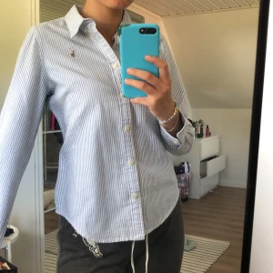 Ralph Lauren skjorta  - Blå och vit randig Ralph Lauren skjorta i fint skick. Storlek 14 men skulle passa xs. Mitt pris är 250 kr. Sänkt pris till 150kr!