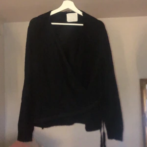 Svart stickad knyttröja  - En svart stickad tröja som man knyter i sidan 