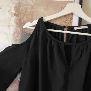  - Snygg svart klänning, med cutouts på axlarna. Som ny✨ Eventuell frakt tillkommer.