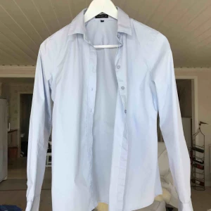  - Fin ljusblå skjorta från märket Stockholm, köpt på en MQ butik. Minimalt använd så väldigt fint skick. Säljer pga för liten för mig..  köparen står för frakten