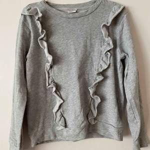 En grå tröja med volanger i storlek S.  Använd några få gånger.  +frakt