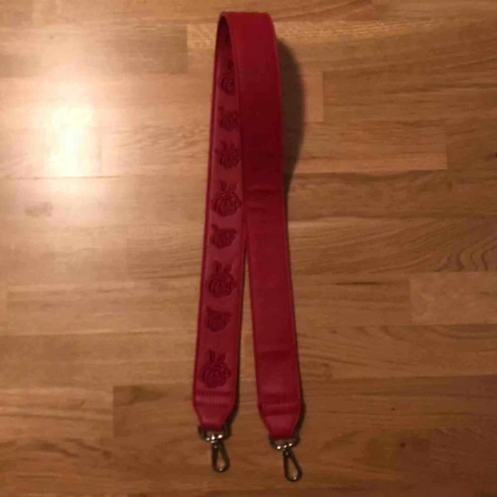 rött väsk-band (det har egentligen rosor på sig men de FÅTAL gånger jag använt det har jag använt det med ”fel” sida (den helt blanka sidan)) 😁. Accessoarer.