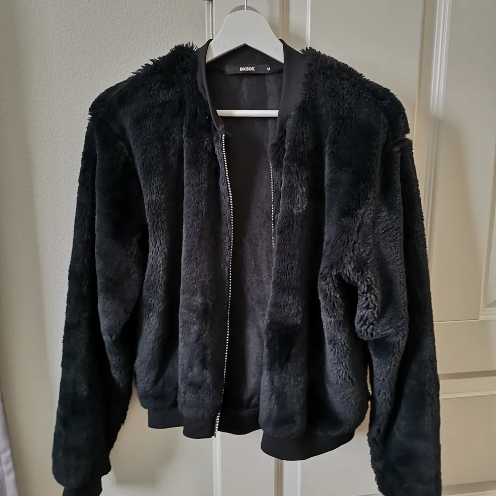 En jacka/tröja i fluffigt svart material . Jackor.