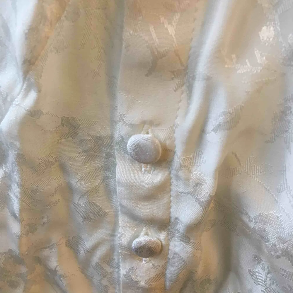 Asfin blus från H&M trend, i vitt lite shiny material (se bild 2). Jättefin modell med halvlånga ballongärmar och knappar längs båda sidorna. Helt oanvänd, lappen kvar! Ursprungspris 300kr.. Blusar.