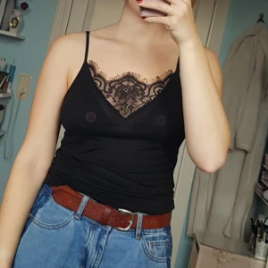  - Tunt svart linne med smala axelband och djup v-ringning med spets