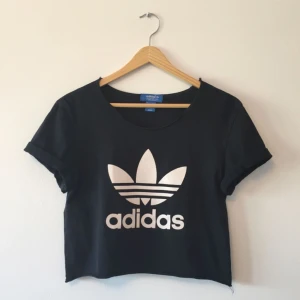  - En croppad t-shirt från Adidas. Den är i en storlek XS från herravdelningen och i damstorlek blir den ungefär en S. I gott skick. 