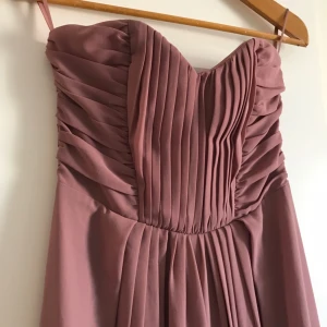  - Superfin axelbandslös lila långklänning från h&m! Endast använd 2 gånger så i mycket bra skick. Säljer då den aldrig kommer till användning.   Fraktkostnad tillkommer!  