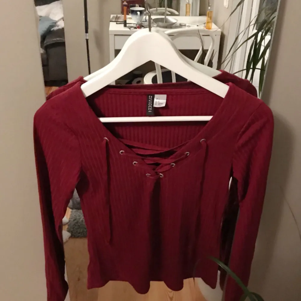Vinröd ”lace-up” tröja från HM. Aldrig använd. Säljs då den är för kort i armarna för mig.. Toppar.