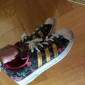  - Adidas Flower. Knappt använda. Blommiga med guldiga streck. Känns som 39or. Köparen står för frakten