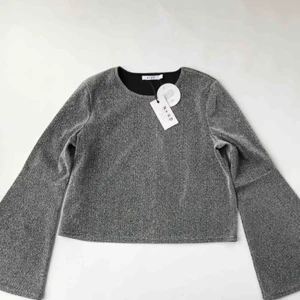  - Oanvänd topp från NA-KD. Silvrig/glittrig med trumpetärmar. 