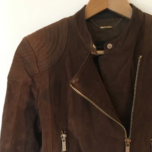  - mc-jacka av äkta mocka med fina detaljer. använt skick, men på ett snyggt sätt imo. hämtas i sthlm eller skickas om du betalar frakt. säljer massor (kmr mycket nytt i dagarna), mängdrabatt finnes! 