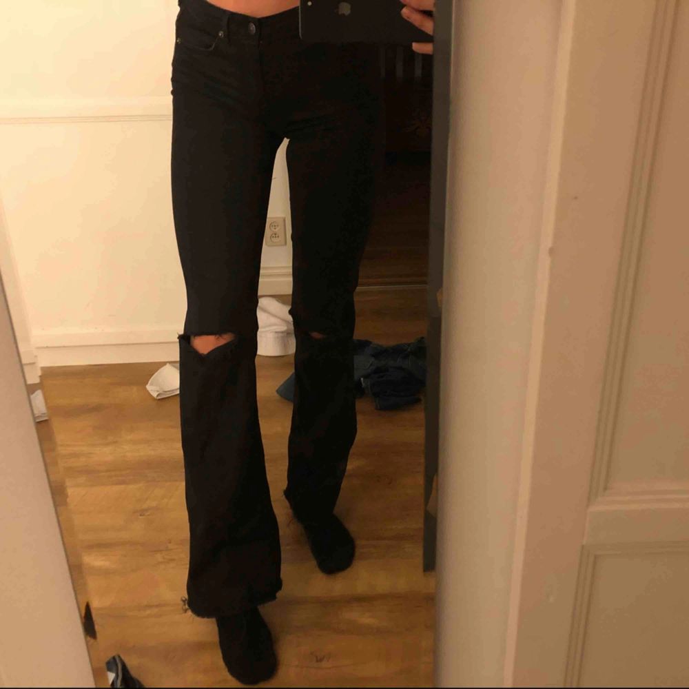 Svarta bootcut jeans från H&M, med hål på knäna. . Jeans & Byxor.