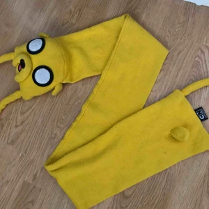  - En halsduk med Jake från Adventure Time/Äventyrsdags på. Ganska sliten eftersom den har varit använd i 1 år och sedan legat i en låda i 2 år till efter det ungefär. Köparen står för frakt.