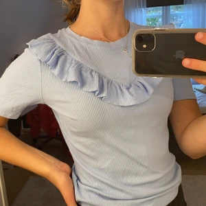 Tröja med volang  - Ljusblå assnygg T-shirt/topp med en volang. Storlek s. Superskönt material och snyggt ribbad. Köpt för 400. Köparen står för frakten🥰🥰 