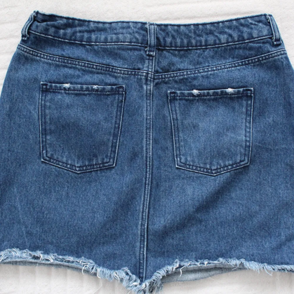 A short, blue, jean skirt - 100% cotton - made in Bangladesh . Kjolar.