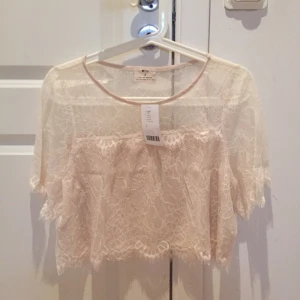  - Beige/gammelrosa/naturvit spetstopp från Urban Outfitters. Aldrig använd, prislapp kvar. Mycket fin ringning och passform på. Fick i present (därav priset borta) men kostade ca 400 kr i nypris. Kan skicka fler bilder vid intresse! 