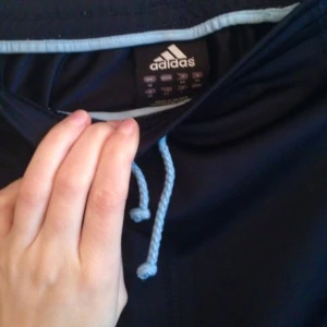  - Adidas original kjol med snöre i midjan och dragkedjsfickor. Första bilden återger färgen bra. Mörkblå med tre ljusblåa ränder på sidorna.  Betalning via Swish, jag möter upp i Sthlm.