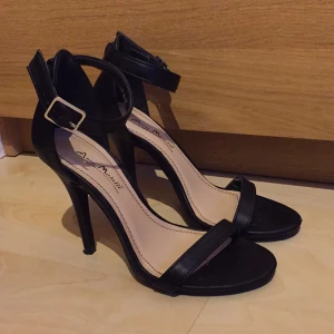  - Svarta höga klackskor med snygga spännen, storlek 36. Sitter riktigt snyggt på fötterna. Endast använda en kväll så ser ut som nya. Perfekta att ha på studenten! Lite höga för mig så därför säljer jag dem.