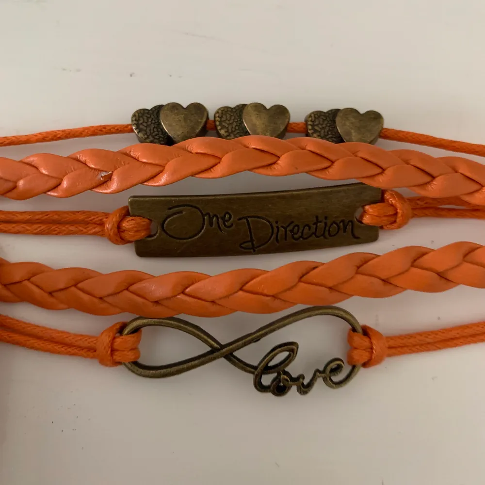 Orange läder(vet ej om det är imitation eller äkta) armband med one direction, justerbart, ej använt, små skav har blivit av att ligga i en låda, färgen visas bäst på första bilden. Accessoarer.