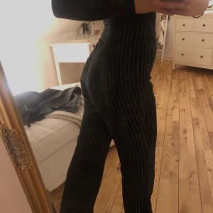 Raka kostymbyxor  - Ett par svarta raka kostymbyxor med vita linjer. Dessa är uppsydda för att passa mig som är ungefär 162 cm.