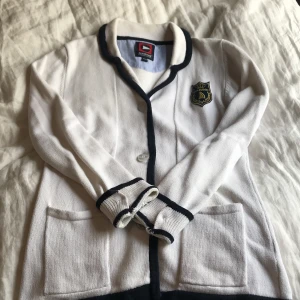 Kavaj Marine - Stickad kavaj med guldemblem. 100 % bomull och superskön. Sitter figurnära när den är stängd. 