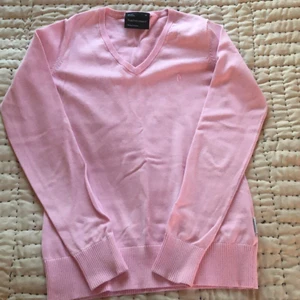 Tröja - En rosa tröja från Peak Performance. Den är långärmad och har en v-ringning längs med halsen.Tröjan är oanvänd och har en bra passform då den sitter lätt på kroppen. 