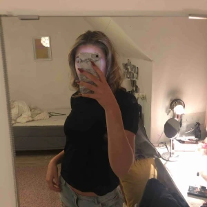  - En svart tshirt topp med detaljer på ryggen