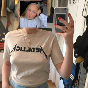  - Beige t-shirt. Står ”Metallica”. Bara använd ett par gånger.