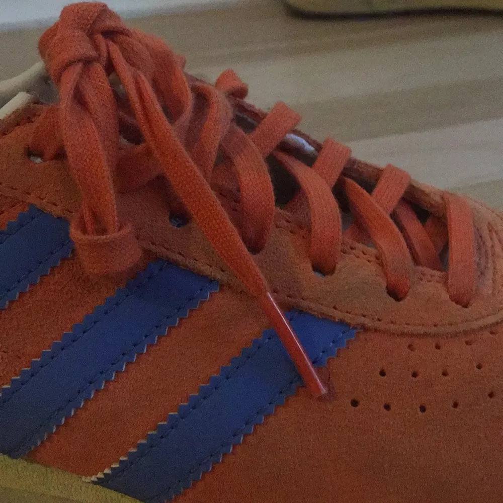Färglada adidas sneakers med ljusgul sula, orange mocka och blå ränder. Skor.